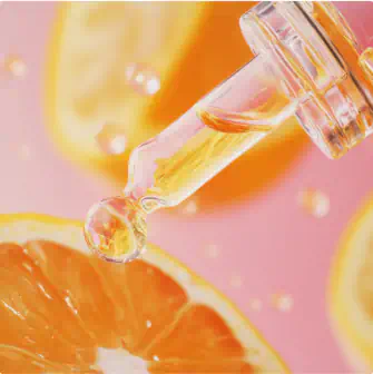 Glass dropper with vitamin C serum above fresh orange slices
