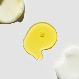 Swatch of yellow avocado oil and creamy skincare products on a white surface