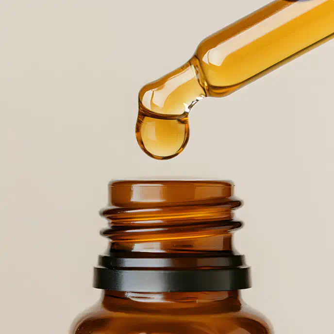 Amber glass dropper bottle with a golden serum droplet