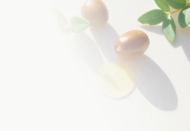 Jojoba seeds, leaves, and golden oil on a light surface