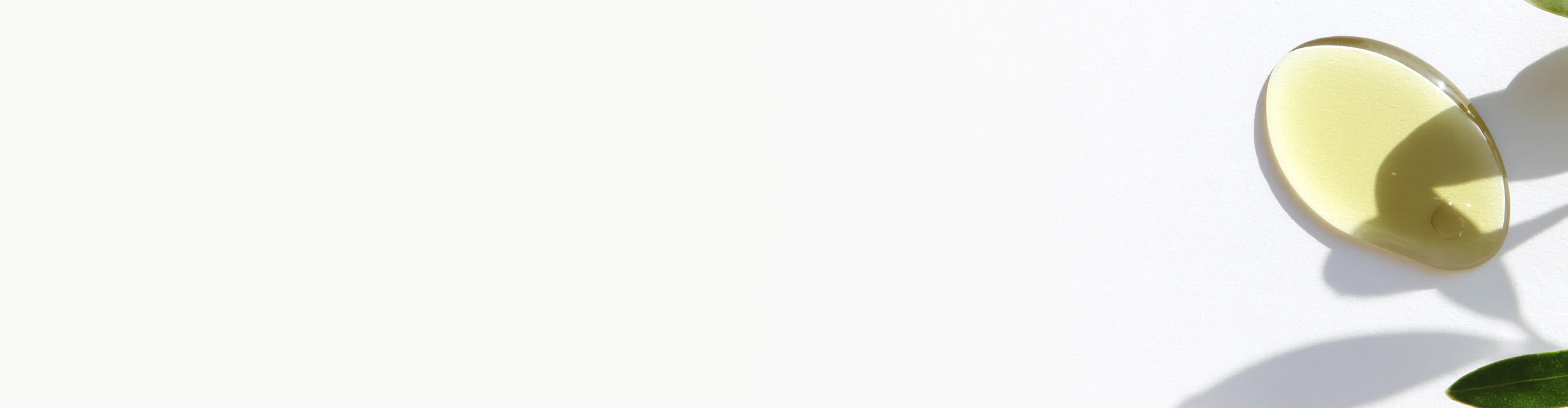 Golden drop of Vitamin E oil on a white surface